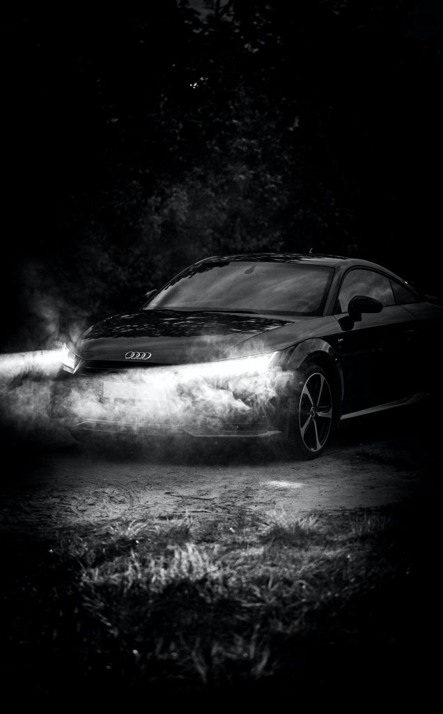 An Audi A3 shinning its lights in the dark so the driver can see through the windscreen.