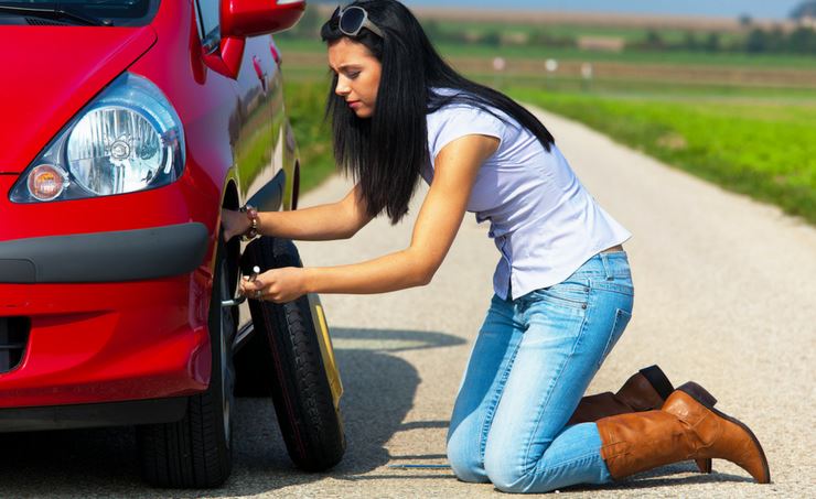 Woman changing the tyre on a red car