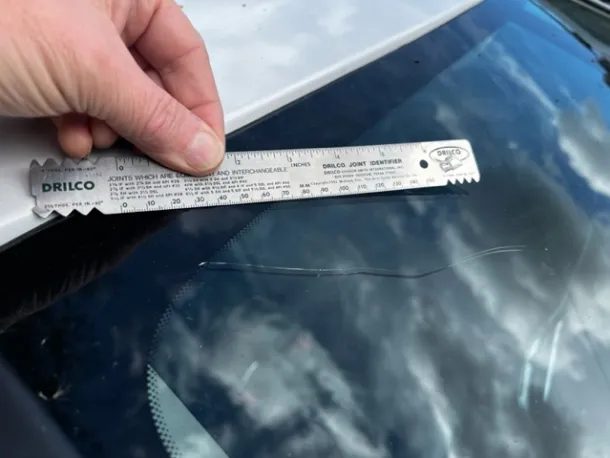 MOT inspector examining a windscreen for damage during a vehicle test